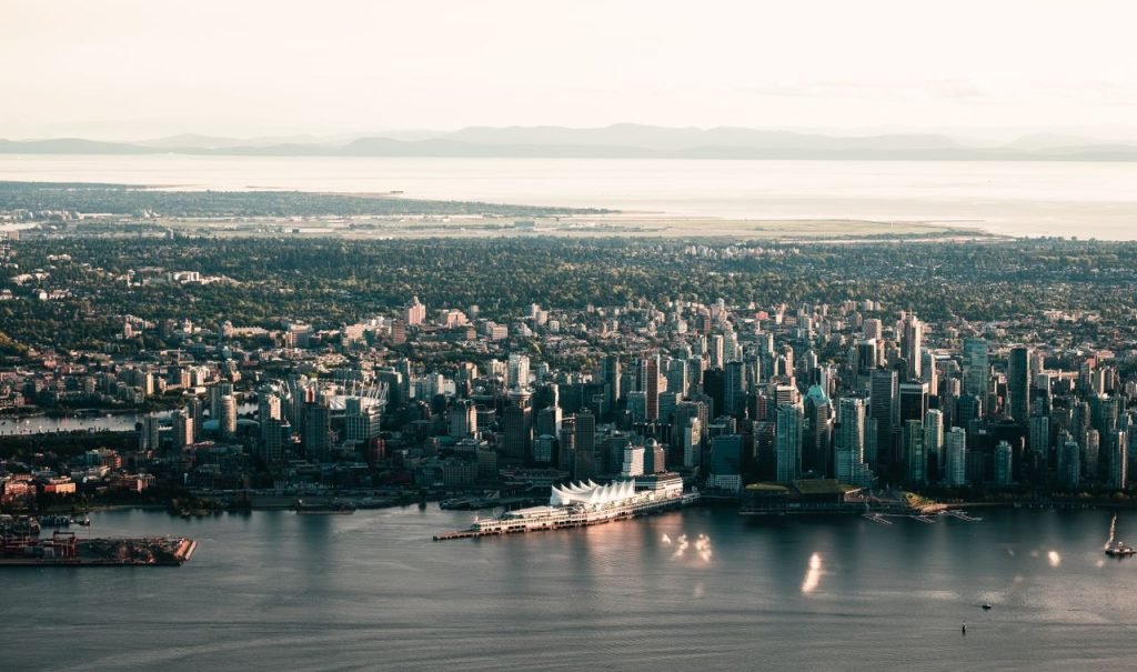 Scenic aerial shot of Vancouvers skyline with waterfront and mountains in the background.
