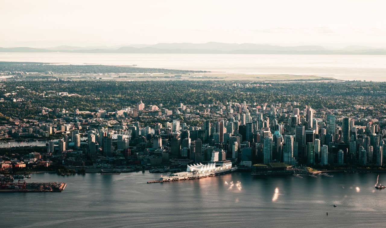Scenic aerial shot of Vancouvers skyline with waterfront and mountains in the background.
