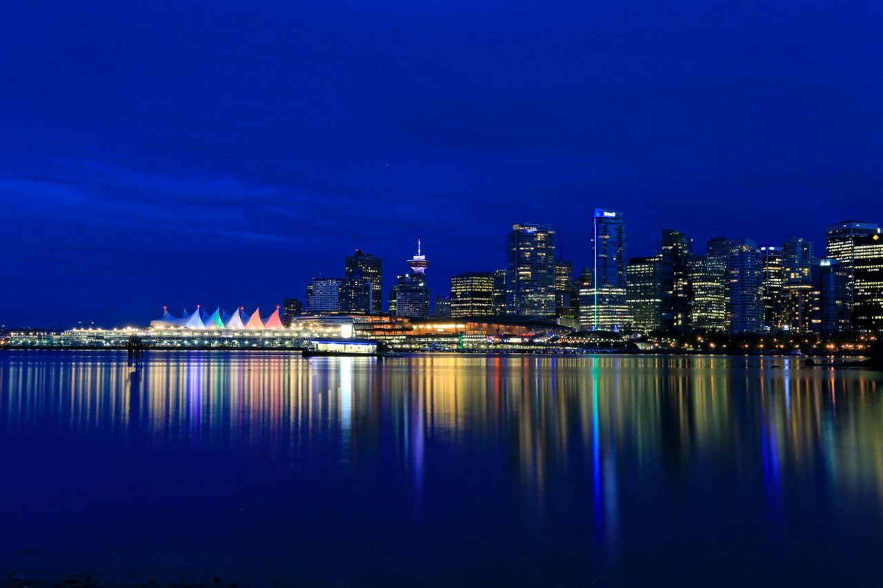 Vibrant night view of Vancouvers illuminated skyline reflecting in the calm waterfront.
